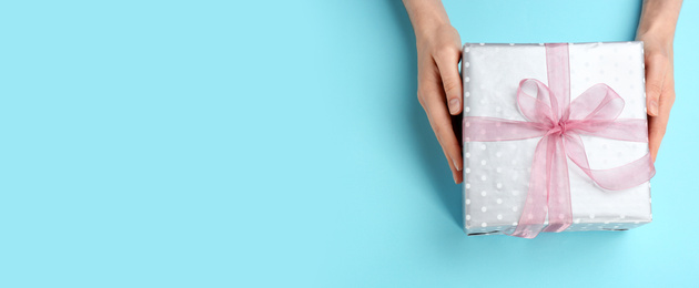 Image of Woman with gift box and space for text on light blue background, top view. Banner design