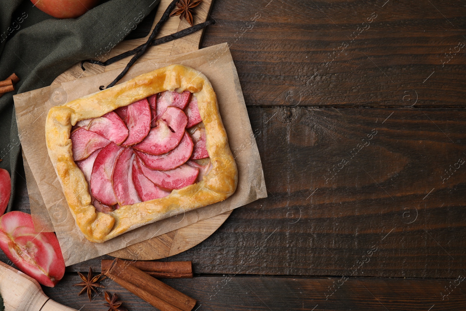 Photo of Delicious galette with apples, spices and fruit on wooden table, flat lay. Space for text