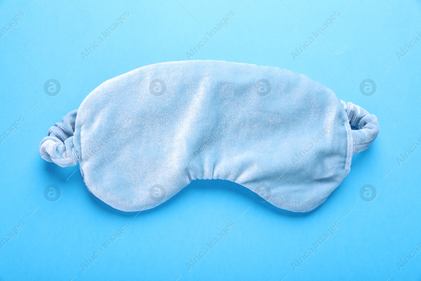 Photo of Soft sleep mask on light blue background, top view