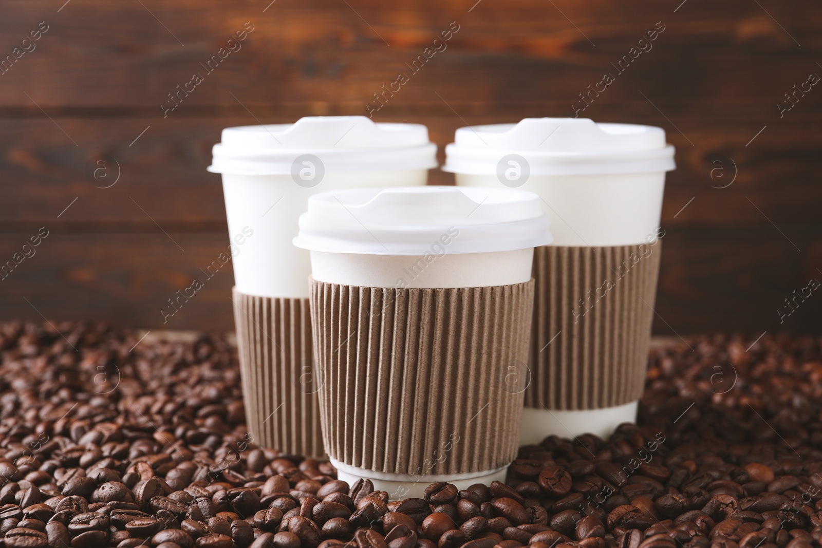 Photo of Coffee to go. Paper cups on roasted beans, closeup