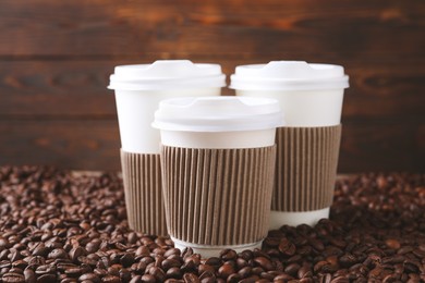 Coffee to go. Paper cups on roasted beans, closeup