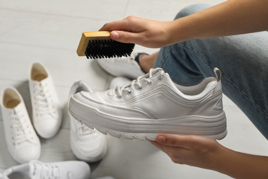 Photo of Woman cleaning stylish footwear indoors, closeup. Shoe care accessory