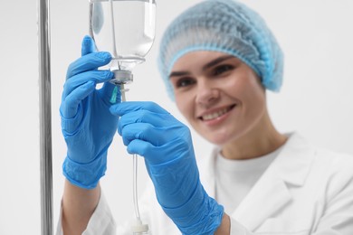 Photo of Nurse setting up IV drip in hospital, selective focus