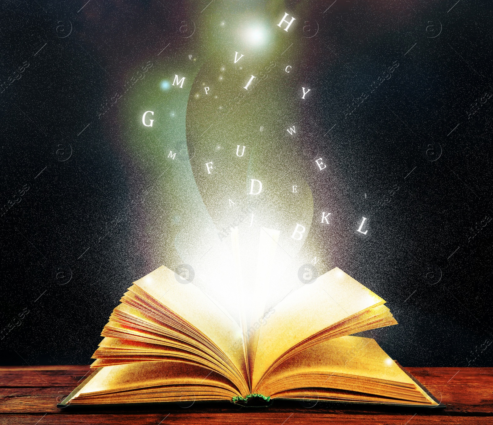 Image of Open book with magic light and glowing letters flying out of it on wooden table against black background