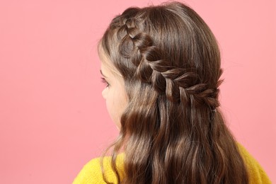 Little girl with braided hair on pink background, back view