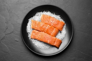 Fresh raw salmon with salt on black table, top view