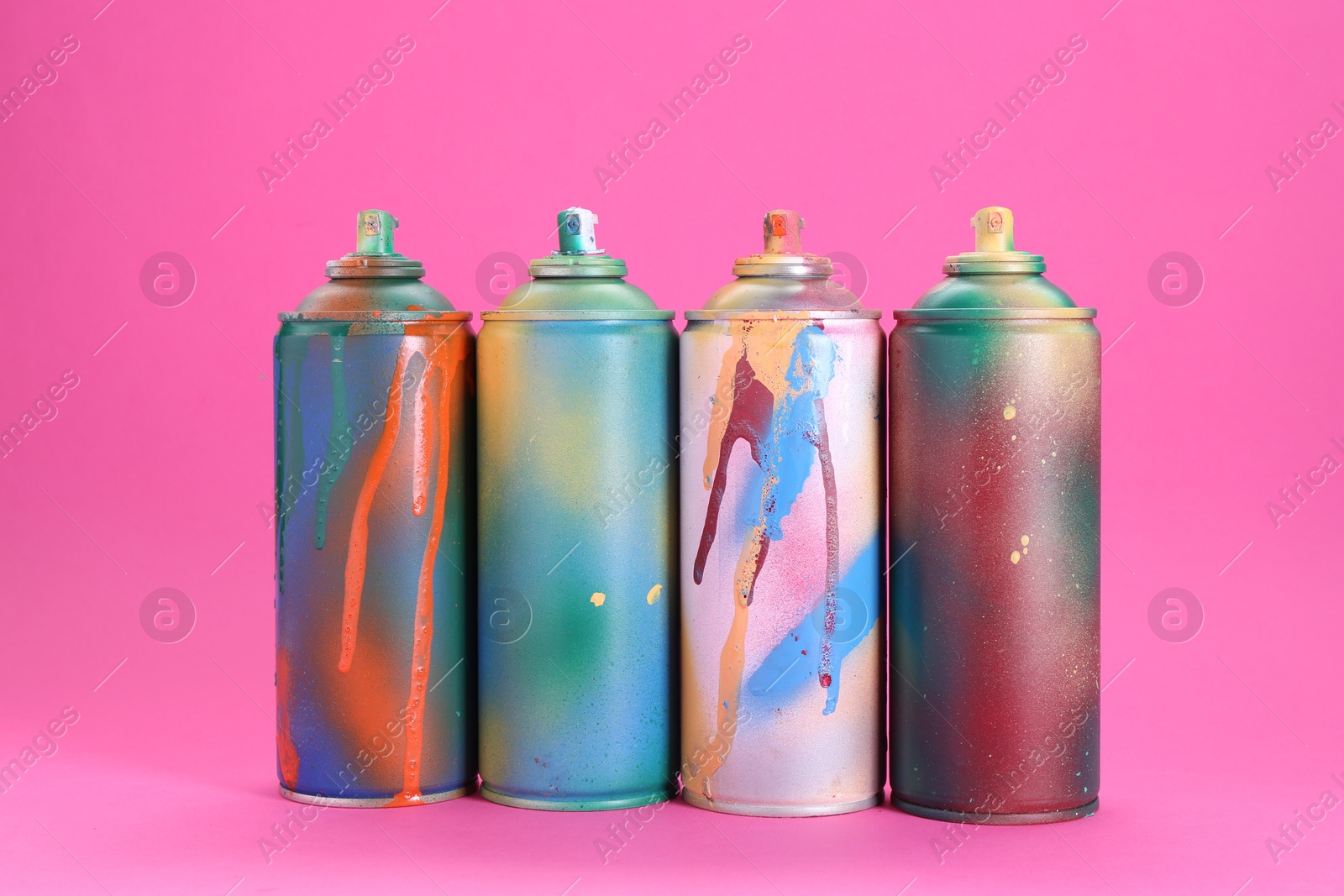 Photo of Many spray paint cans on pink background