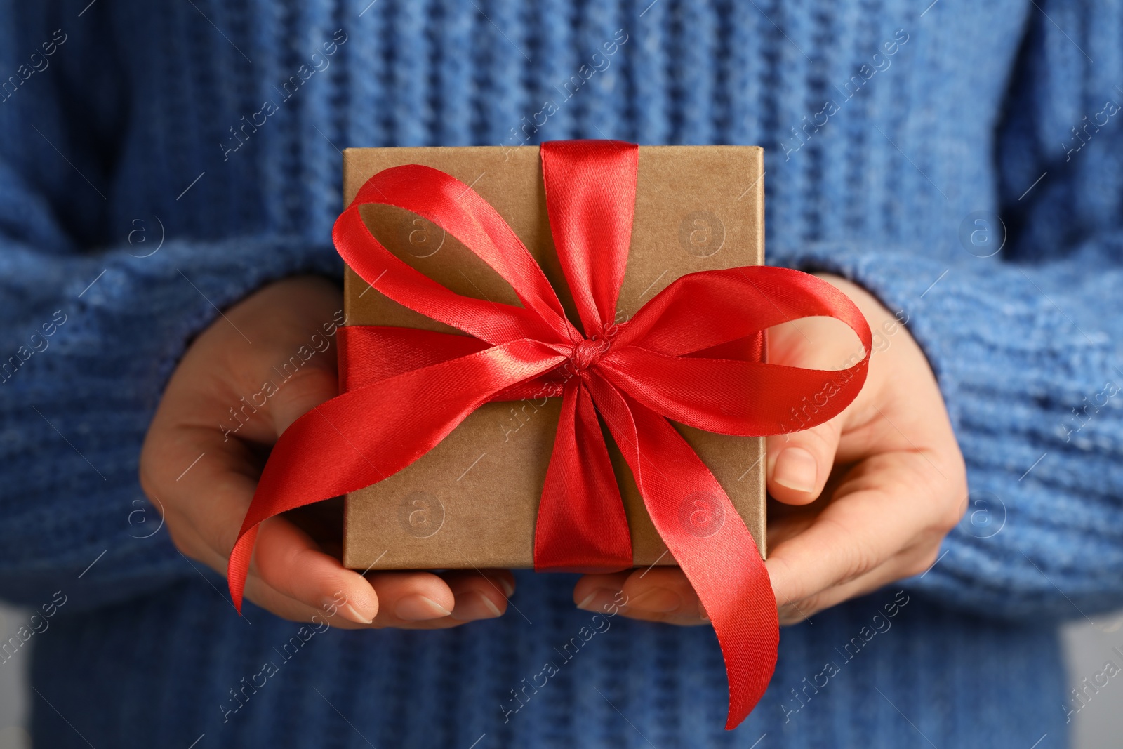 Photo of Woman holding gift box with red bow, closeup