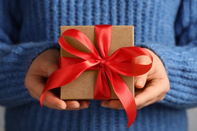 Photo of Woman holding gift box with red bow, closeup