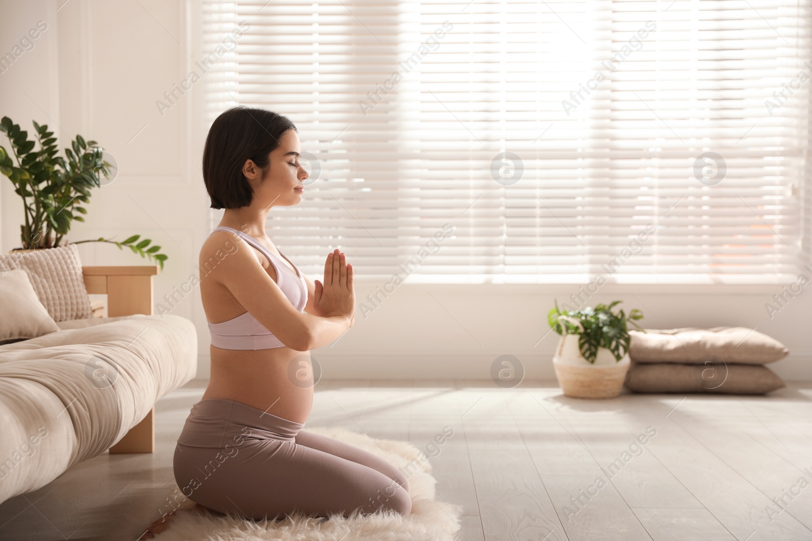 Photo of Young pregnant woman practicing yoga at home, space for text