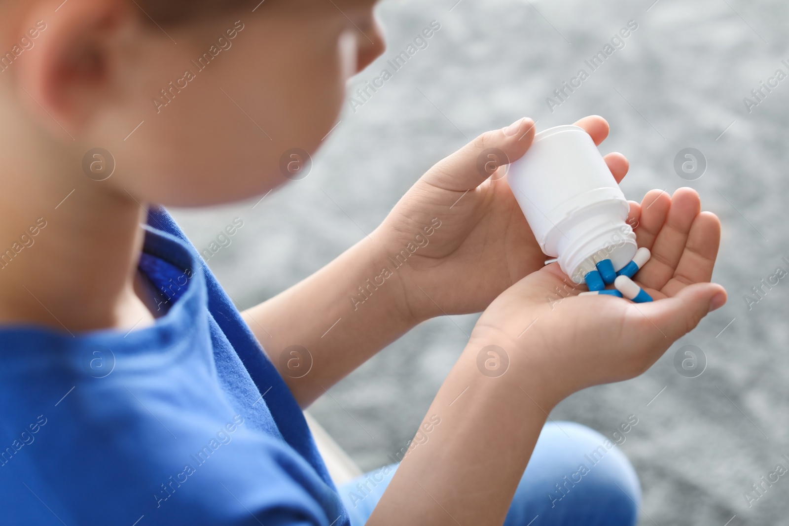 Photo of Little child with pills at home, closeup. Danger of medicament intoxication