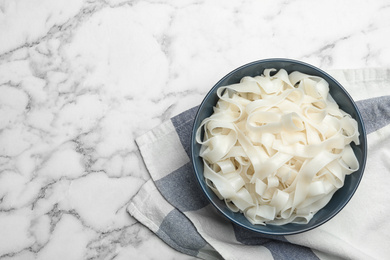 Photo of Rice noodles on white marble table, flat lay. Space for text