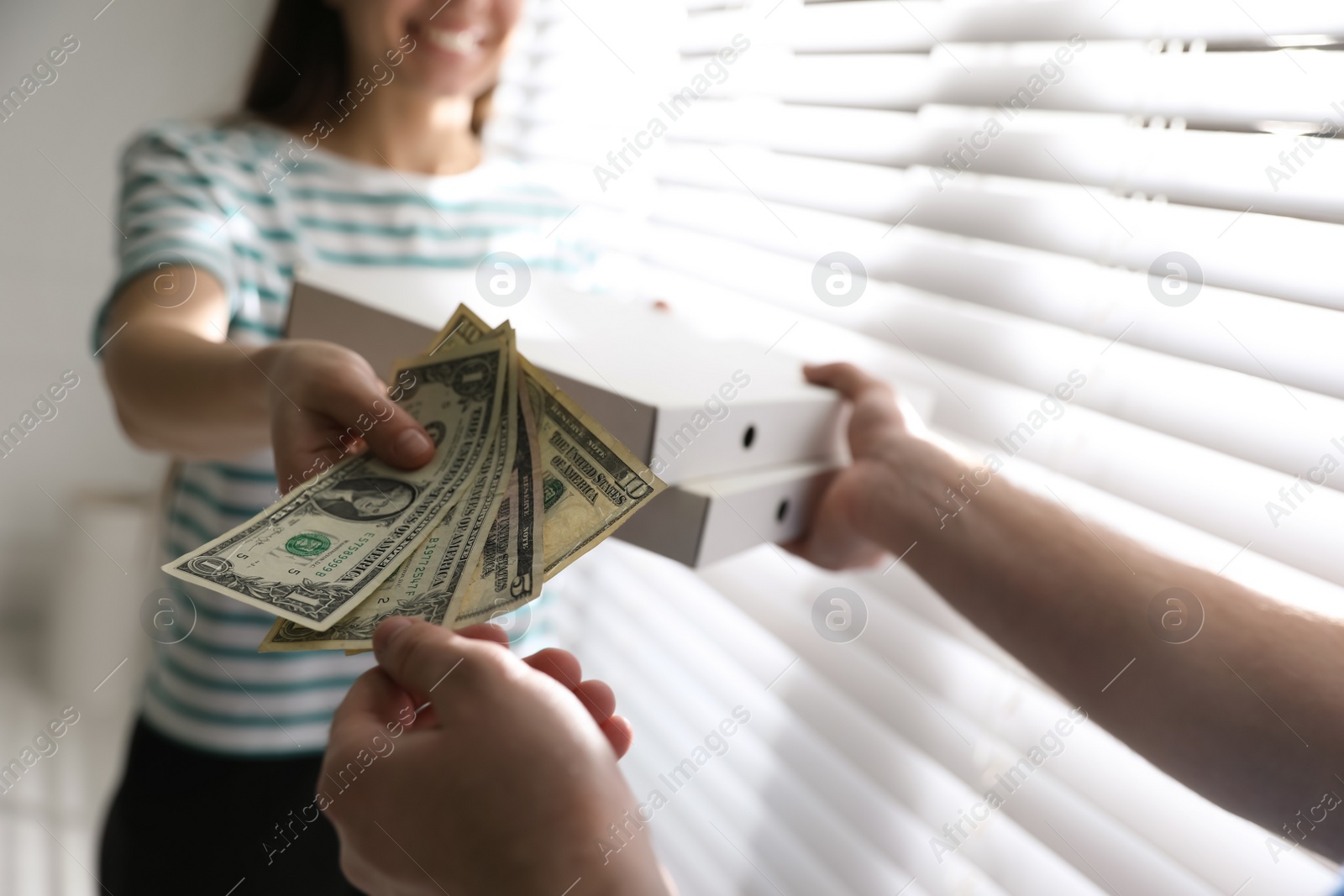 Photo of Woman giving tips to deliveryman indoors, closeup