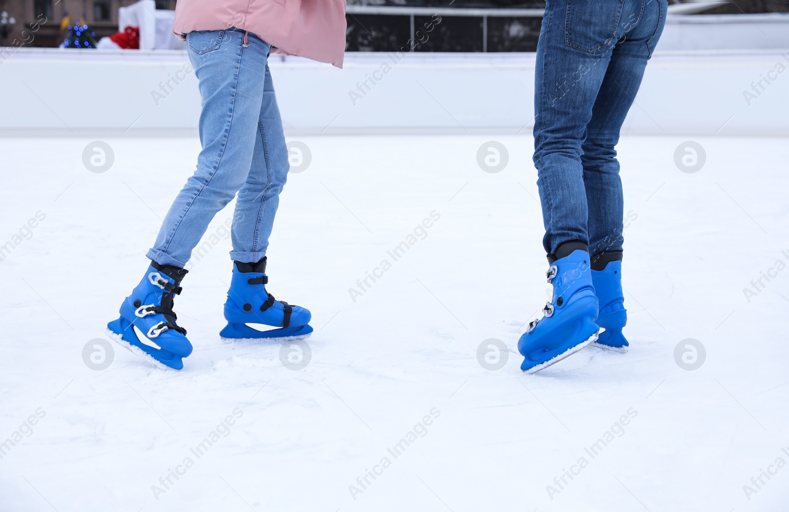 Image of Couple skating along ice rink outdoors, closeup