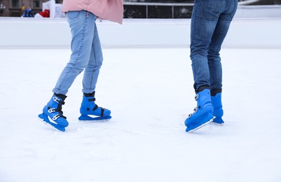 Couple skating along ice rink outdoors, closeup