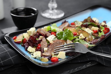 Photo of Delicious salad with beef tongue, cheese and fork served on black table, closeup
