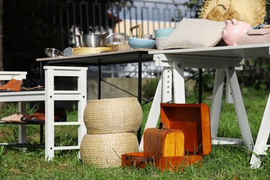 Photo of Small tables with many different items on garage sale outdoors