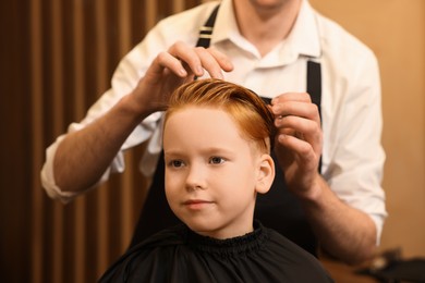 Professional hairdresser working with boy in beauty salon, closeup
