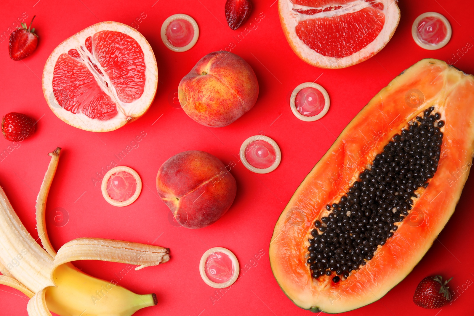 Photo of Flat lay composition with condoms and exotic fruits on red background. Erotic concept