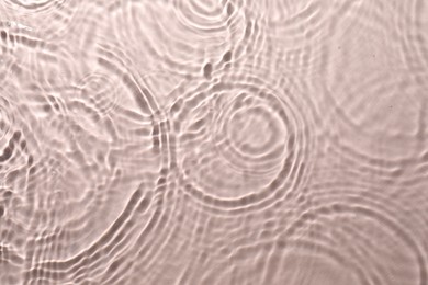 Rippled surface of clear water on beige background, top view