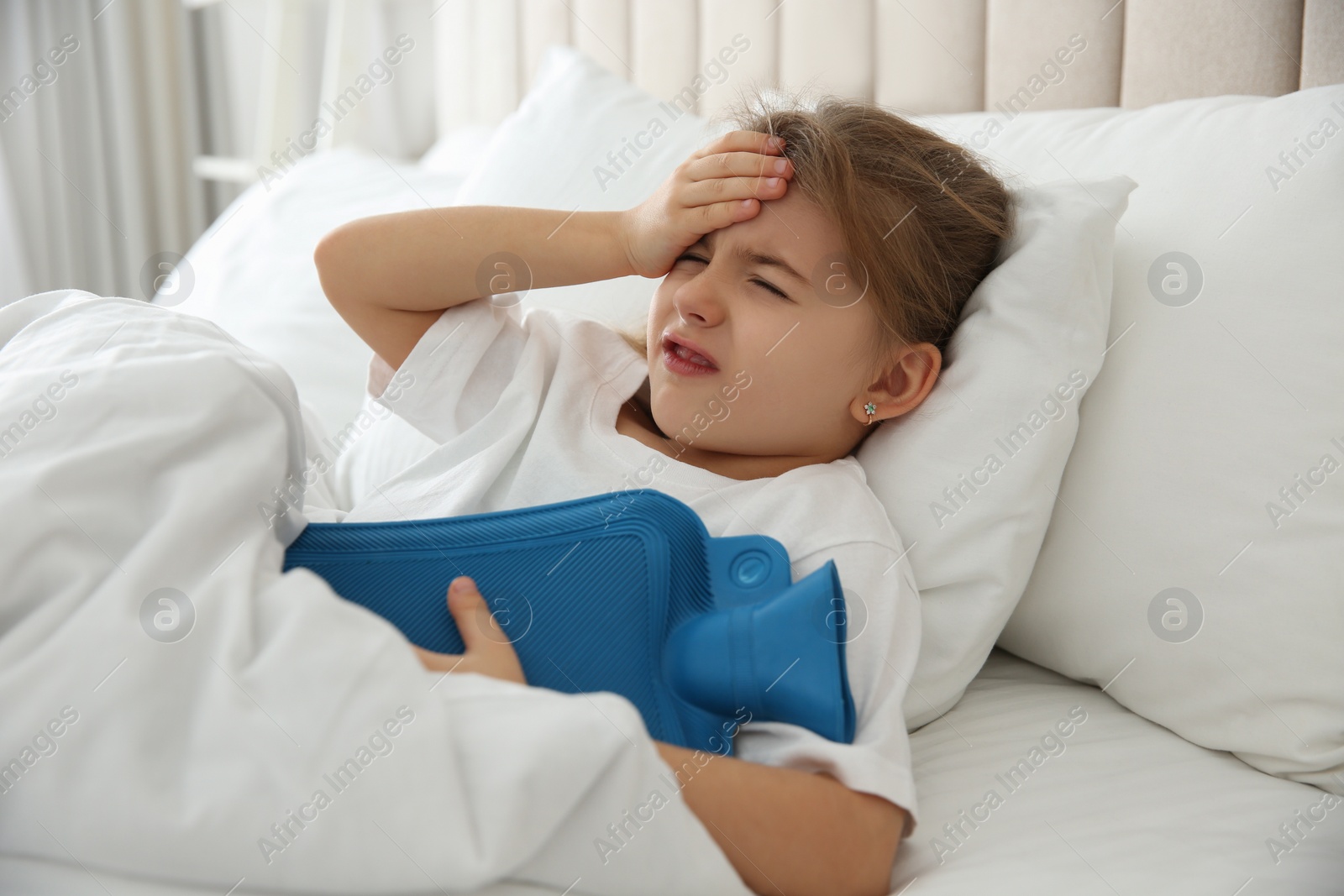 Photo of Ill girl with hot water bottle suffering from cold in bed at home