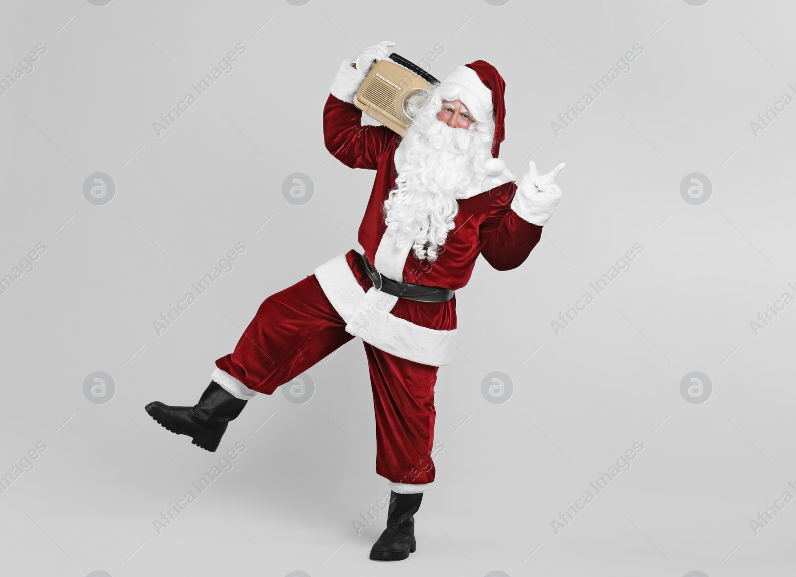 Photo of Santa Claus with vintage radio on light grey background. Christmas music