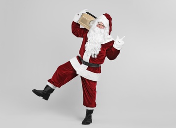 Photo of Santa Claus with vintage radio on light grey background. Christmas music