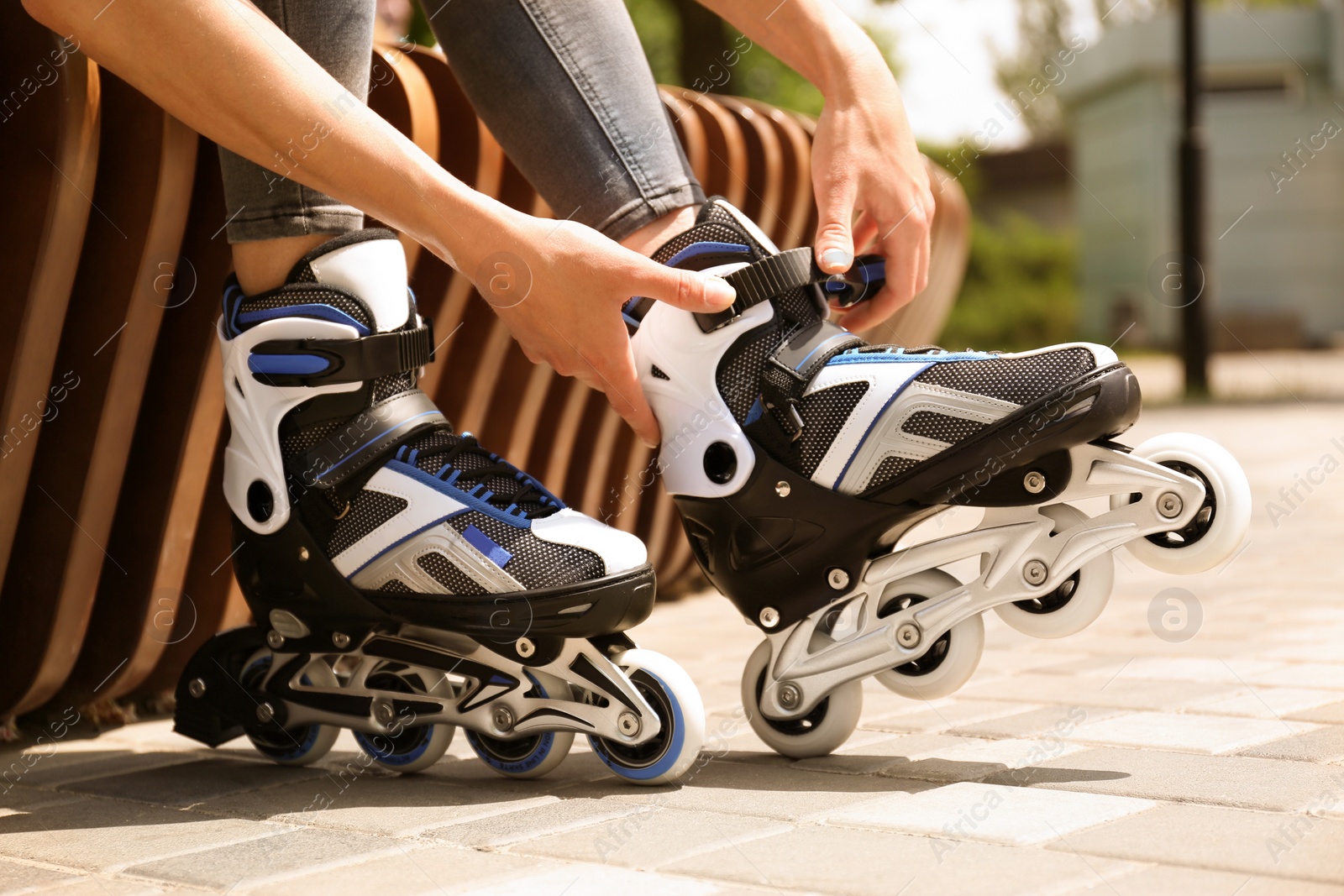 Photo of Woman wearing modern inline roller skates in city park, closeup