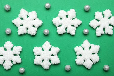 Photo of Beautiful decorative snowflakes and decor on green background, flat lay