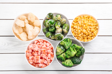 Photo of Different frozen vegetables on white wooden table, flat lay