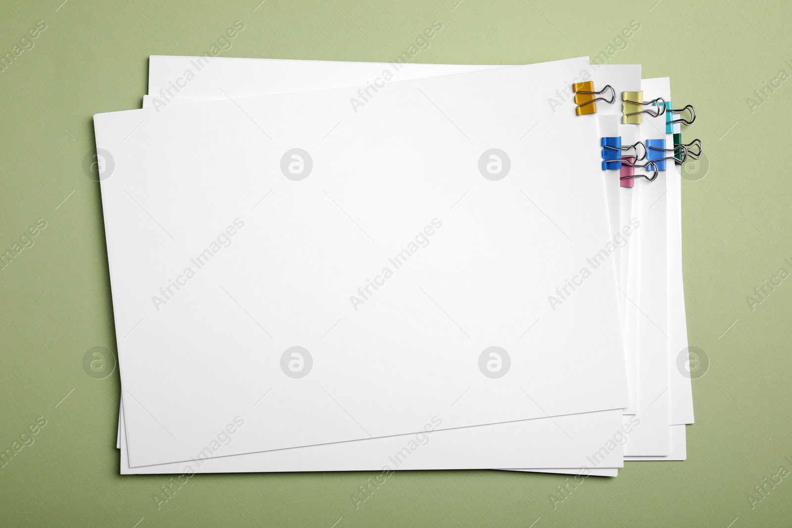 Photo of Sheets of paper with clips on light green background