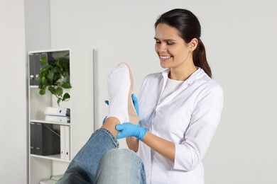 Beautiful female orthopedist fitting insole to patient's foot in hospital