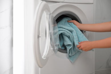 Photo of Woman putting dirty laundry into washing machine indoors, closeup