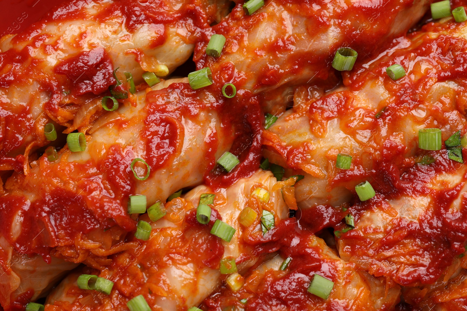 Photo of Delicious stuffed cabbage rolls cooked with homemade tomato sauce as background, top view