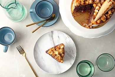 Delicious homemade cake with caramel sauce and tableware on light background, top view