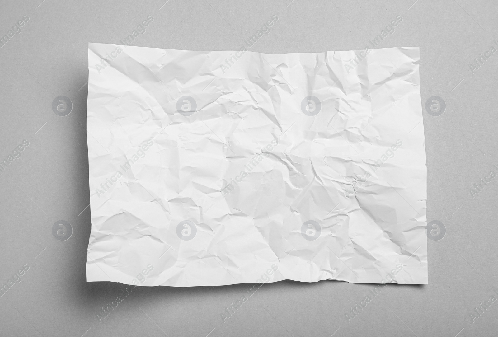 Photo of Sheet of white crumpled paper on grey background, top view