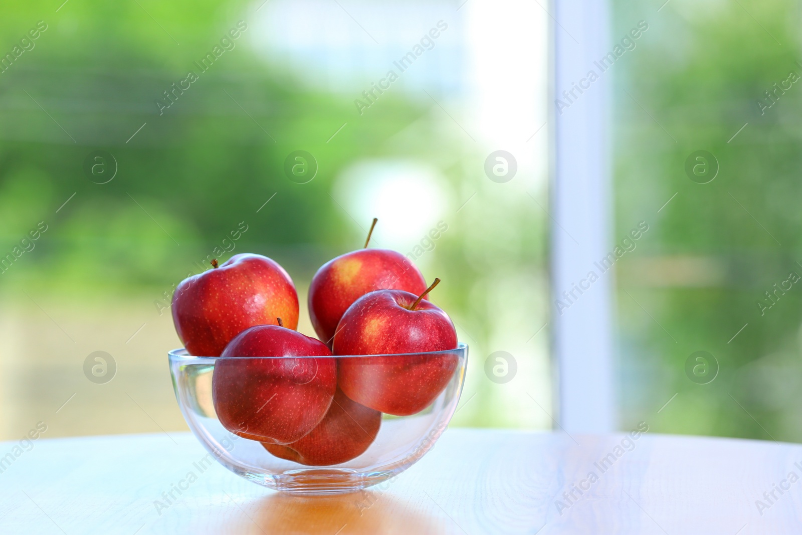 Photo of Bowl of fresh red apples on table indoors. Space for text