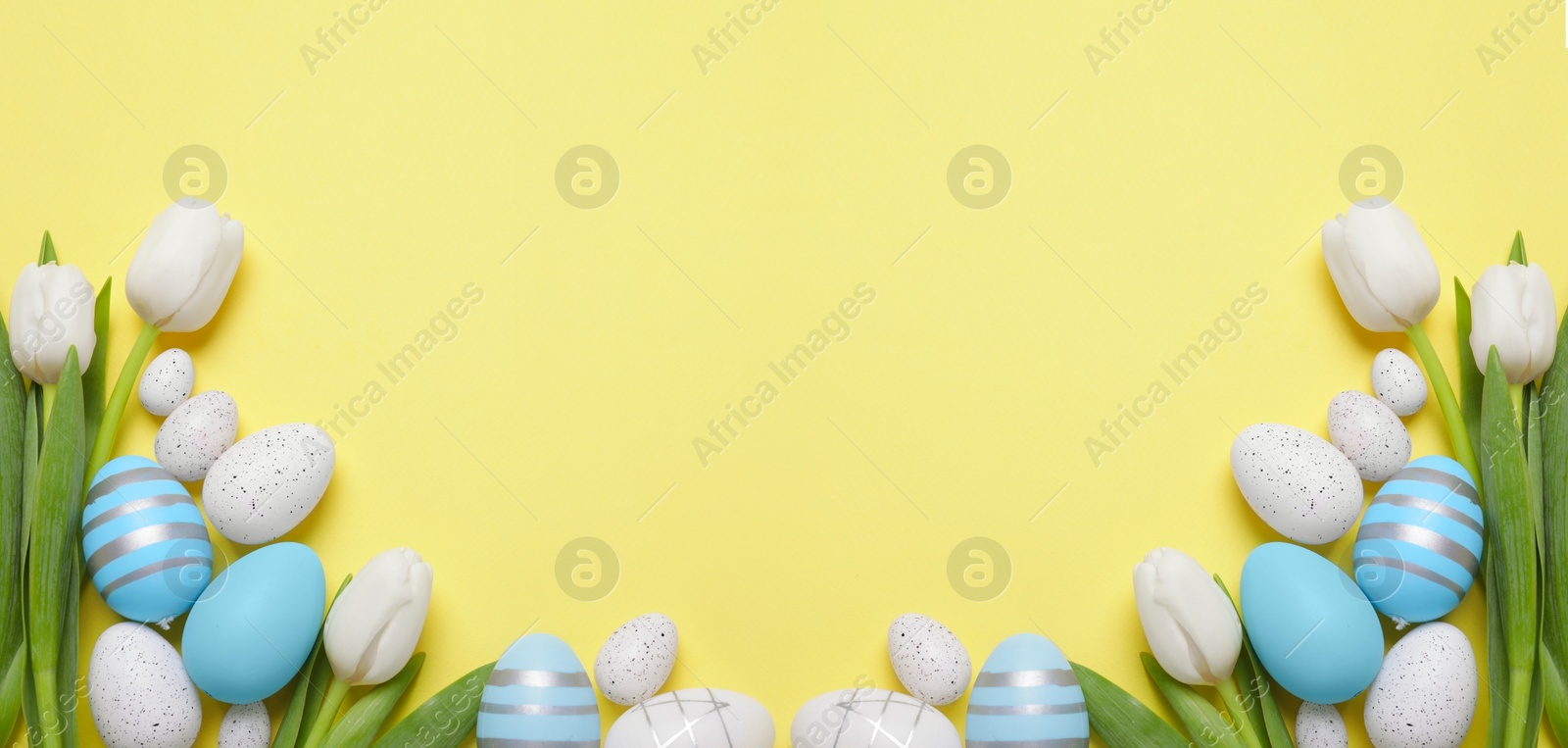 Image of Flat lay composition with decorated Easter eggs and flowers on pale yellow background, space for text. Banner design