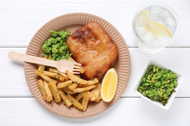 Photo of Tasty fish, chips, peas and lemon on white wooden table, top view