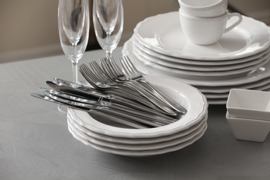 Photo of Set of clean dishware, cutlery and champagne glasses on grey table 