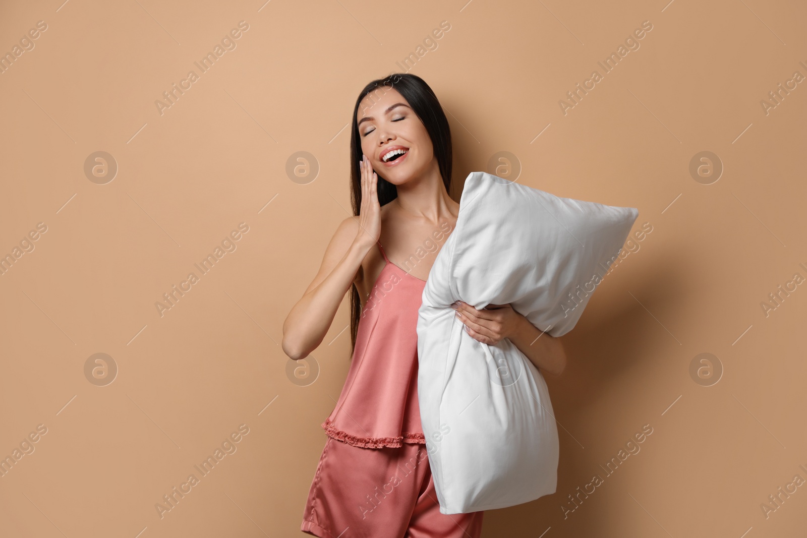 Photo of Beautiful Asian woman with pillow on beige background. Bedtime