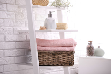 Photo of Basket with clean towels on shelving unit in bathroom