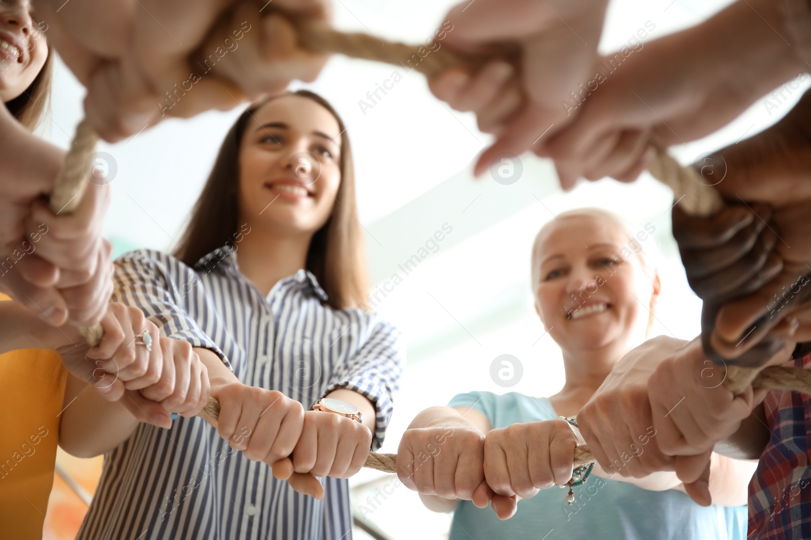 Photo of People holding rope together on light background, closeup of hands. Unity concept