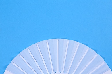 Photo of White hand fan on light blue background, top view. Space for text