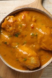 Photo of Tasty chicken curry on wooden table, top view