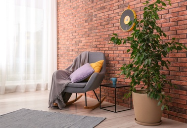 Photo of Stylish room interior with armchair and potted ficus