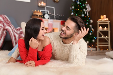 Happy young couple lying on floor at home. Christmas celebration