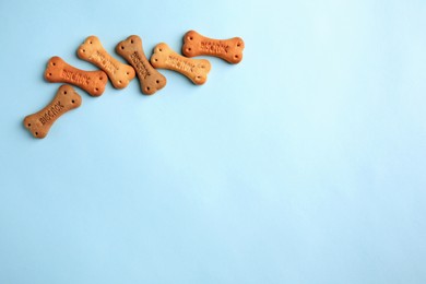 Photo of Bone shaped dog cookies on light blue background, flat lay. Space for text
