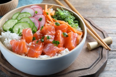 Delicious poke bowl with salmon and vegetables served on table, closeup