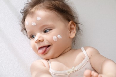 Cute little baby with cream on face in comfortable crib, top view